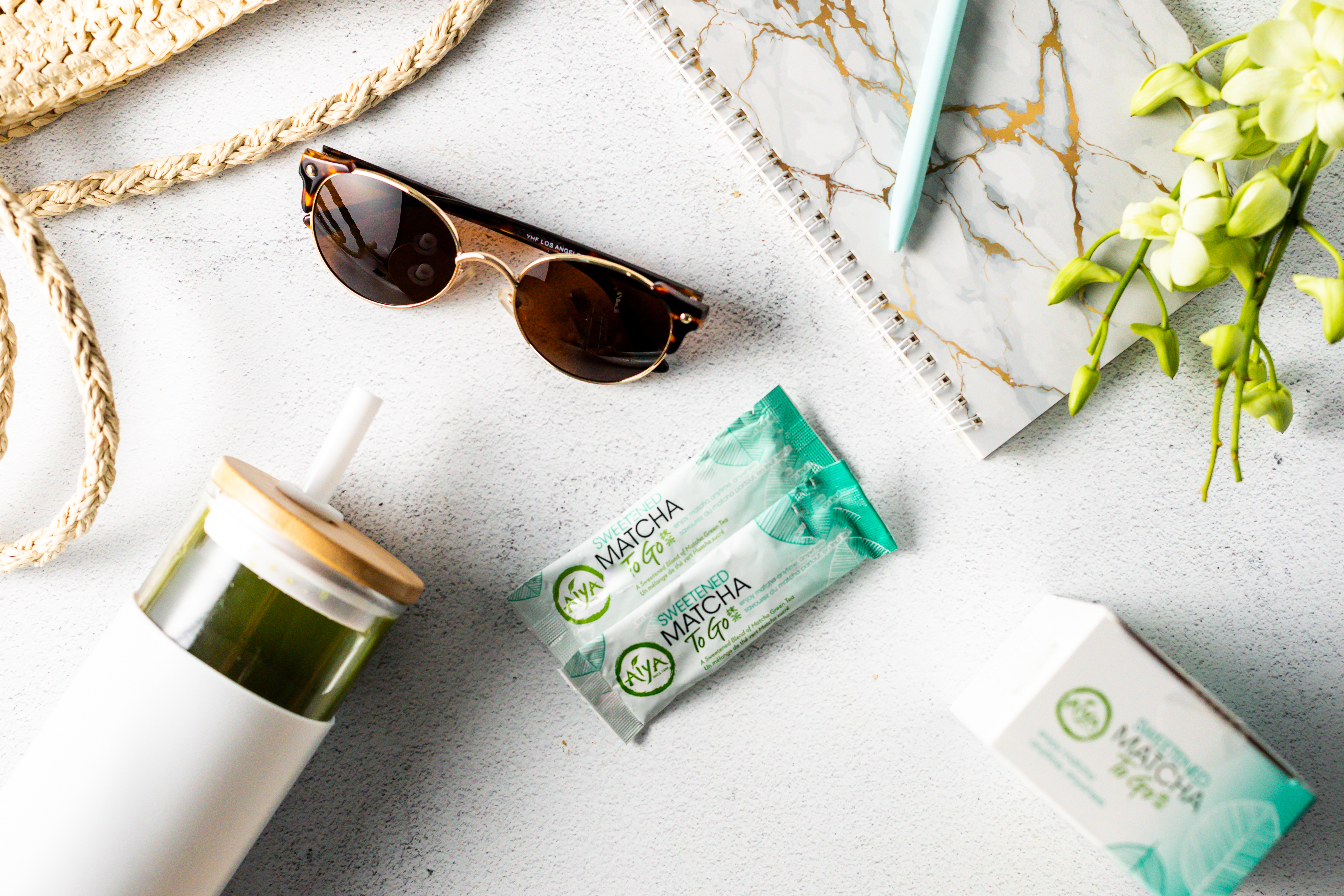 Sweetened Matcha To Go with handbag, sunglasses, and other travel essentials